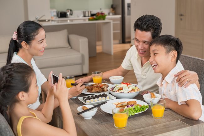 Girl taking photo of her father and brother at the dinner table